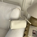Détail du sac cylindrique en cuir grainé blanc cassé posé sur un canapé blanc élégant - Blanc
