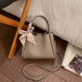 Close-up of beige lychee grain leather handbag with decorative scarf and logo detail - Gray