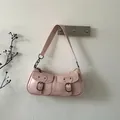Close-up of a pink vintage leather shoulder bag with retro bronze buckle pockets - Pink