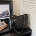 Detail einer schwarzen glänzenden Stepptasche mit goldener Metallkette und Lederriemen - Schwarz