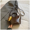 Dark brown faux leather bucket bag with unique round handle and beaded charm detail - Brown