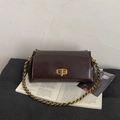 Detail der dunkelbraunen glänzenden Ledertasche mit goldener Schließe und Kette - Braun