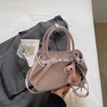 Vista detallada del bolso rosa con colgante de caballo y cinta de rayas en cama blanca - Rosa (Con Colgante)