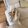 Dettaglio della borsa a secchiello in pelle beige con ciondolo a orsetto e fibbie dorate - Bianco con ciondolo