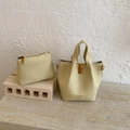 Détail du sac seau en cuir crème avec fermoir rotatif doré et texture grainée - Jaune sans pendentif