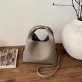 Vista dettagliata della borsa in pelle taupe con grana litchi su un tavolo di legno - Grigio