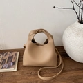 Dettaglio della texture in pelle granata sulla borsa a secchiello beige di alta qualità - Cachi