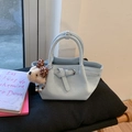 Détail du sac seau en cuir bleu clair avec boucle à ruban et charm chien en peluche - Bleu avec Pendentif