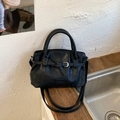 Detailed close-up of soft black leather tote with pleated design and metallic strap buckle - Black