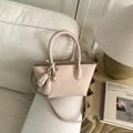 Dettaglio della borsa a secchiello beige con trama a grana e nappa decorativa - Rosa