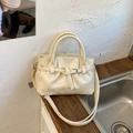 Detalle de bolso tipo cubo crema con asas dobles, correa con hebilla de metal y logo - Blanco