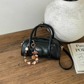 Close-up of a glossy black mini Boston bag with colorful star charms on a wooden table - With Charm / Black