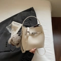 Detailansicht der cremefarbenen Eimer-Tasche aus Leder mit Schloss und Hasenanhänger - Gebrochenes Weiß