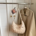 Detail view of beige quilted puff shoulder bag with zipper pocket on a metal stand - Off-white