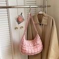 Close-up of pink quilted puffer shoulder bag hanging on metal rack in lifestyle setting - Pink