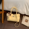 Bolso saco de cuero amarillo con cierre plateado y accesorio de colgante de osito suave - Amarillo con colgante