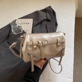 Detail der beige Zylindertasche mit Nieten und Quasten in minimalistischem Design - Khaki