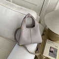 Dettaglio della trama in pelle martellata e hardware dorato su questa borsa a secchiello - Grigio