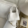 Dettaglio della borsa in pelle martellata bianca con finiture dorate in un ambiente elegante - Bianco