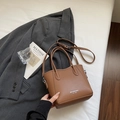 Sac seau marron avec grain de litchi, poignées et logo dans un cadre de style de vie - Sans Pendentif / Marron