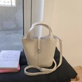 Detail van gebroken witte emmertas in lychee-textuur leer met zilveren metalen slot - Wit Zonder Hanger