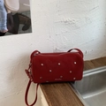 Nahaufnahme der dunkelroten Handtasche mit silbernen Sternnieten und glatter Ledertextur - Rot