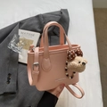 Rosafarbene Eimertasche aus genarbtem Leder mit Tragegriffen und süßem Bär-Anhänger-Detail - Roze mit Anhänger