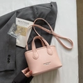 Pink pebbled leather bucket bag with top handles and adjustable strap on a grey suit jacket - Pink Without Pendant
