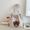 Dettaglio del ricamo dell'orso e della toppa sulla borsa tote in tela beige con coulisse - Cachi Chiaro