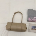 Dettaglio ravvicinato di una borsa a cilindro beige con spalline lunghe e texture in PU opaco - Cachi