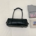 Detail view of black cylindrical shoulder bag with wide strap on minimalist background - Black