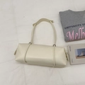Borsa tote minimalista in pelle beige esposta su tessuto con oggetti di scena e outfit casual - Bianco