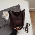 Détail du sac seau vintage avec motif texturé, bandoulière en cuir et étiquette mode - Café