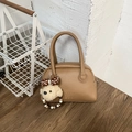 Dettaglio di borsa bowling in pelle marrone con ciondolo a forma di cane in peluche - Marrone con ciondolo