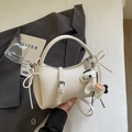 Detail of a minimalist white leather handbag with a chic pony-shaped decorative charm - Cream White With Pendant