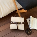 Close-up of cream textured leather handbag with brown trim and vintage buckle detail - White