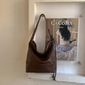 Dettaglio macro della borsa a spalla in pelle marrone con coulisse laterali decorative - Marrone