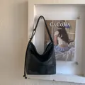Dettaglio di una grande borsa a secchiello in pelle nera opaca con coulisse e tracolla regolabile - Nero