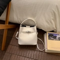 Detailed close-up of a cream white bucket bag with metallic buckle on a wooden floor - No Pendant / White