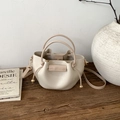 Detail of minimalist cream bucket bag with gold ball charm and drawstring on wood - Khaki
