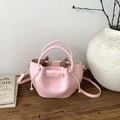 Detailed macro view of pink bucket bag with gold hardware on a rustic wooden platform - Pink