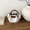 Detail of white bucket bag with brown handle and leather texture on a wooden table - White