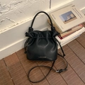 Detalle de bolso tipo cubo negro plisado con cierre de cordón y logo Favor & Stories - Negro