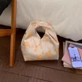 Detail of a retro jacquard knot bag with orange floral patterns on a satin surface - Yellow