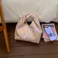 Detail einer Satin-Handgelenktasche mit Blumenmuster in Gelb auf hellviolettem Stoff - Rosa