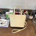 Creamy yellow leather bucket bag with short handle and long crossbody strap in a home setting - Yellow Without Pendant