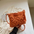 Close-up of handmade orange macrame shoulder bag featuring bohemian tassels and woven texture - Orange
