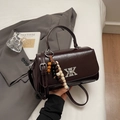 Details einer glänzenden braunen Ledertasche mit silberner XK-Schnalle und Holzperlen - Kaffeebraun