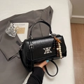 Detail einer schwarzen glänzenden Lederhandtasche mit Silberbeschlägen und Perlenanhänger - Schwarz