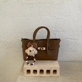 Close-up of brown pebbled leather handbag with gold metal clasp and plush bear charm - Brown (With Pendant)